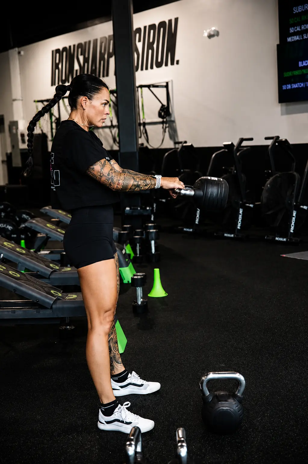 An athlete mid kettlebell swing under the IRON SHARPENS IRON wall